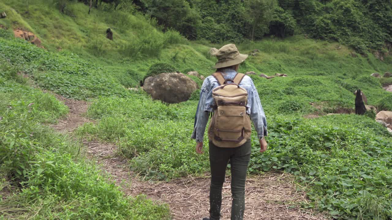 4K亚洲女性背包客在小溪边的山路上徒步旅行视频素材