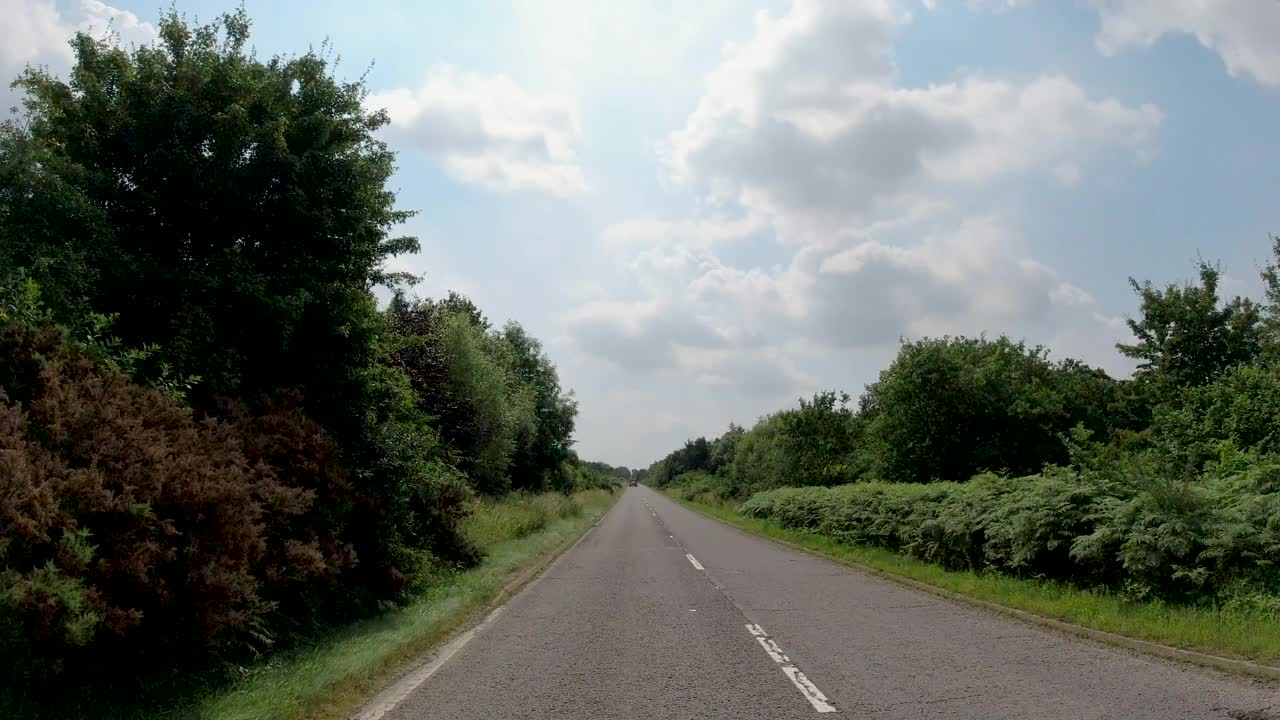 4K延时POV汽车在漫长的乡村公路上行驶，被拖拉机困在后面，英国，英国。农场，田野和树篱路在一个阳光灿烂的蓝天。非城市场景的观点视频素材