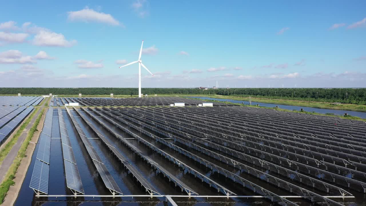 平原地区的太阳能发电站和远处的风力涡轮机。中国江苏省盐城市视频素材