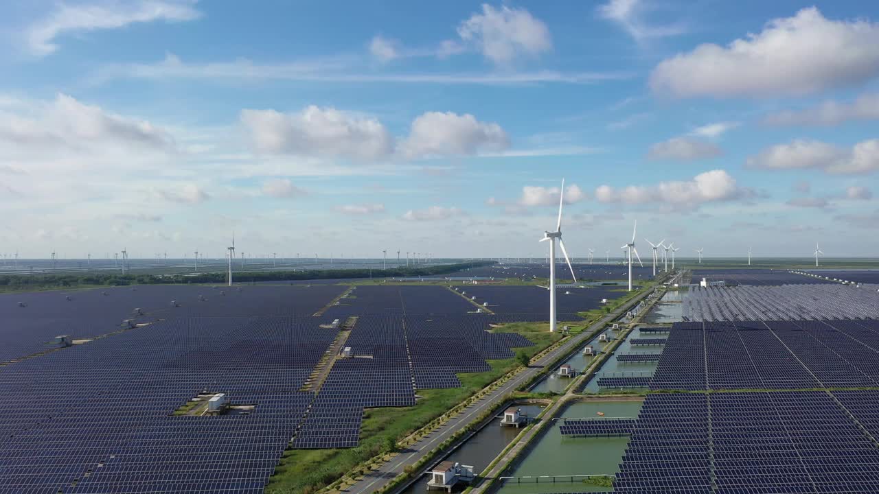 平原地区的太阳能发电站和远处的风力涡轮机。中国江苏省盐城市视频素材