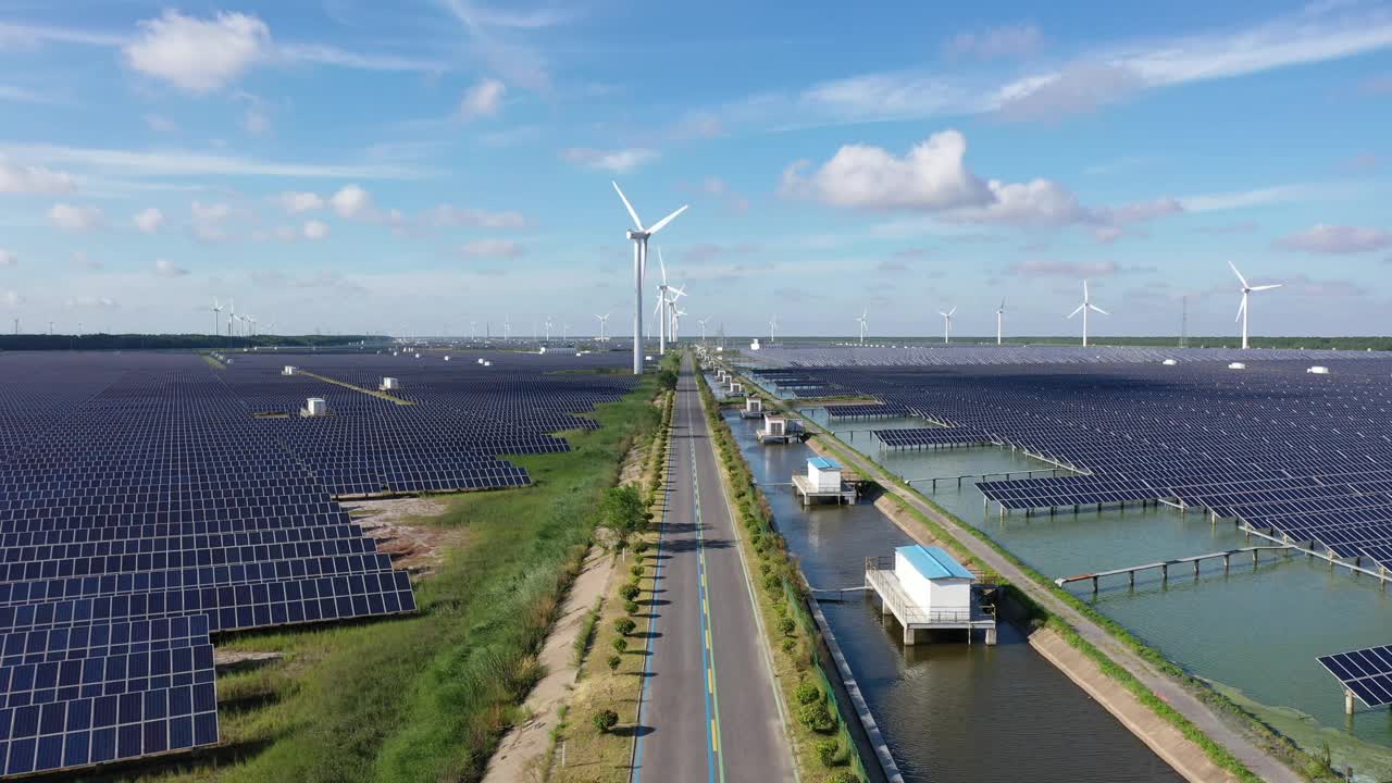 平原地区的太阳能发电站和远处的风力涡轮机。中国江苏省盐城市视频素材