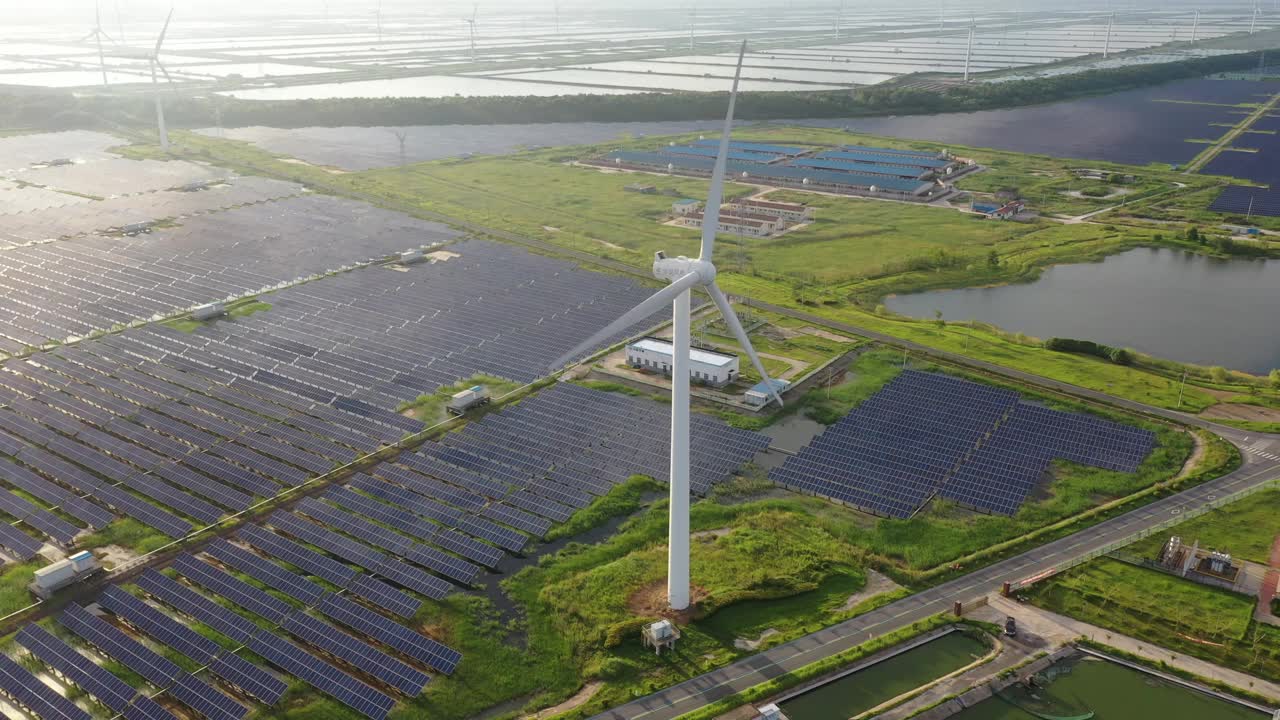 高大的风力涡轮机正在运转，地面上的太阳能发电站也在运转。中国江苏省盐城市视频素材