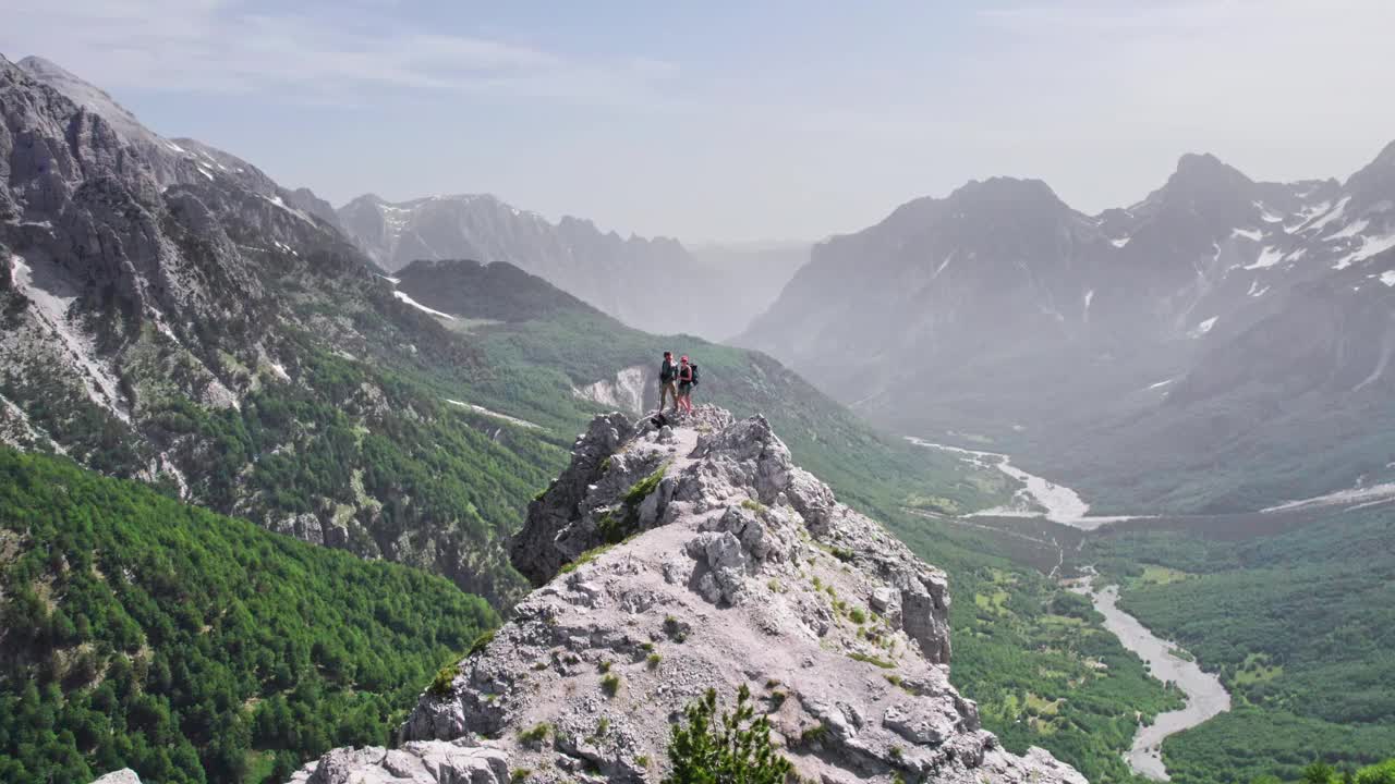 一对徒步旅行者在山顶上的令人惊叹的景色。男人和女人环顾四周，欣赏壮丽的山景。旅行,成功,团结视频素材