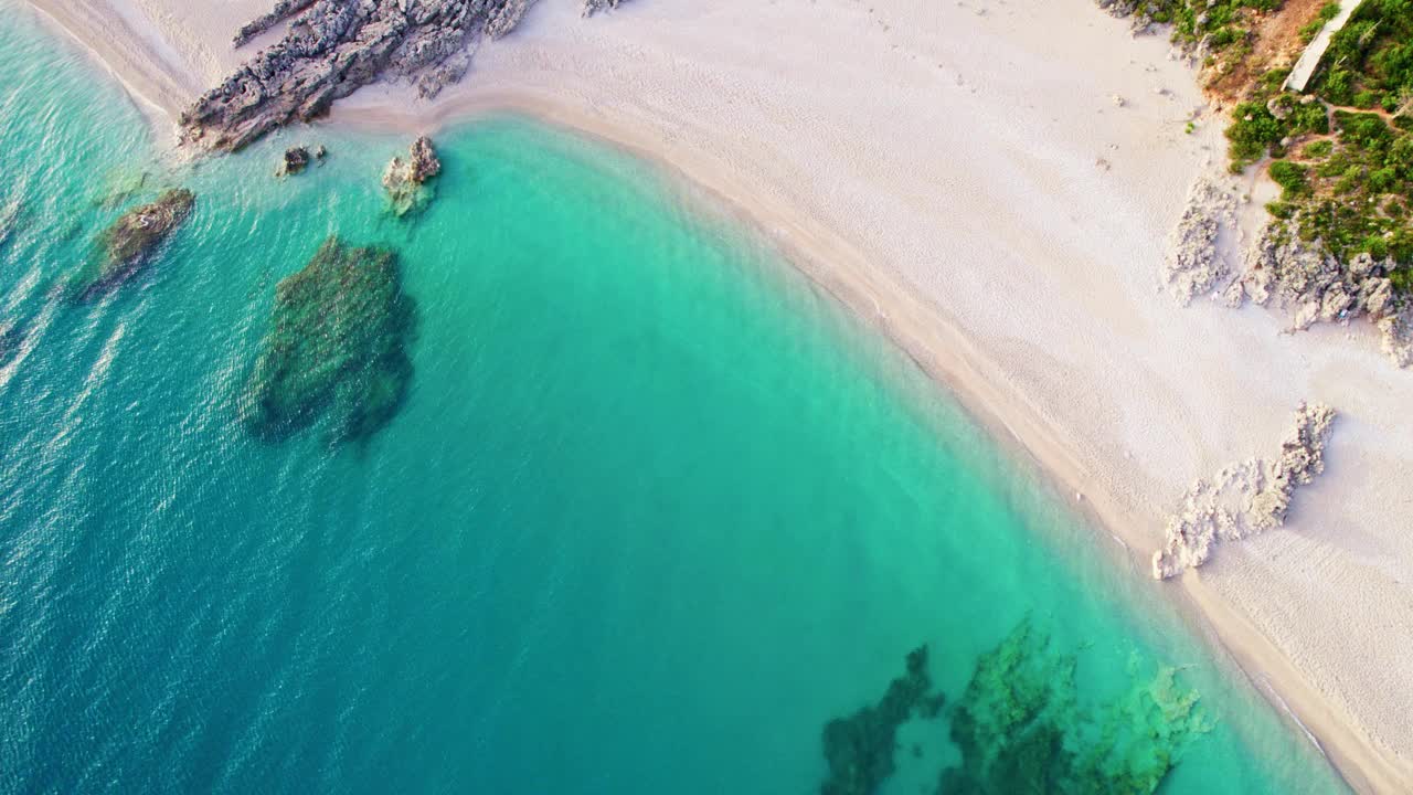 美丽的沙滩和蓝绿色的海水。鸟瞰图的大海，沙滩和岩石。这是一个僻静的放松和娱乐的好地方视频素材