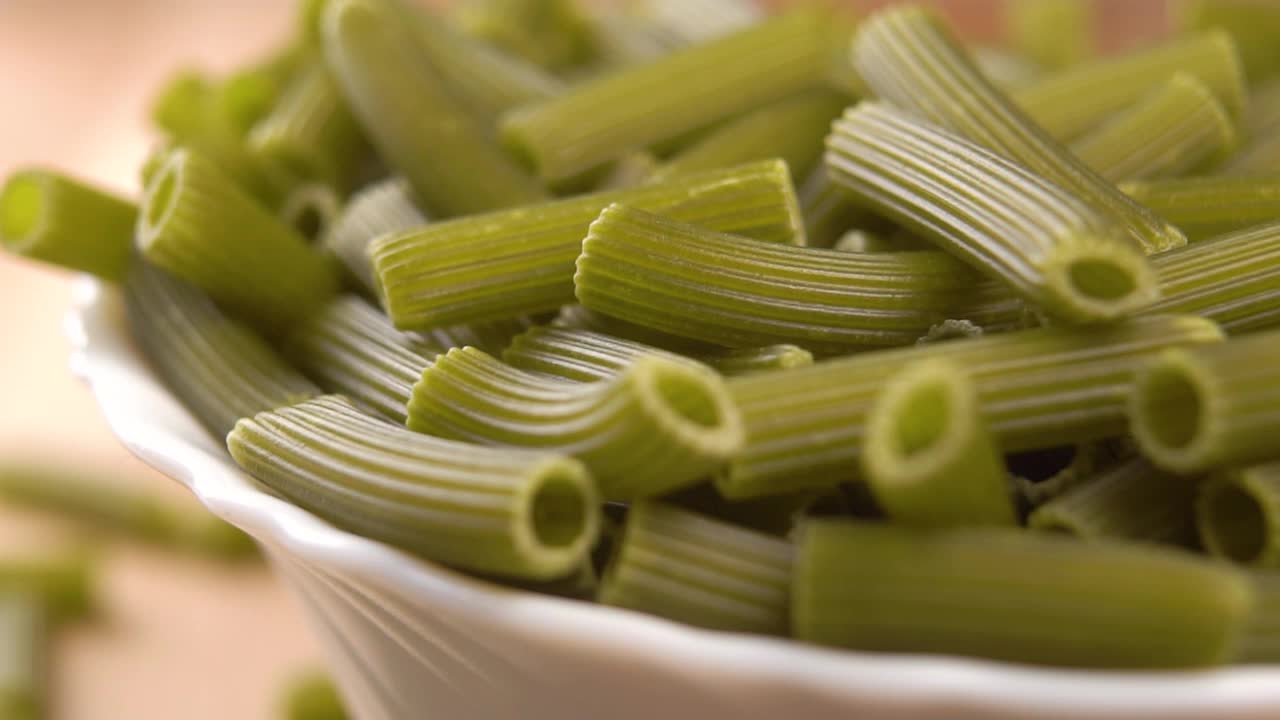 绿色生豌豆菠菜蔬菜素食面食。把通心粉倒在白色的碗里视频素材