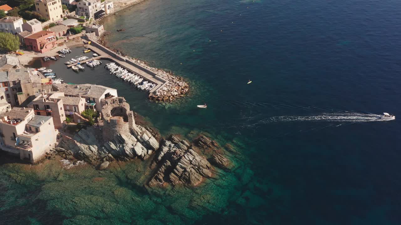 科西嘉岛特色石村港口鸟瞰图。生动的蓝色的大海。鸟瞰图的海岸，美丽的大海，房屋，树木在阳光明媚的夏日。视频素材