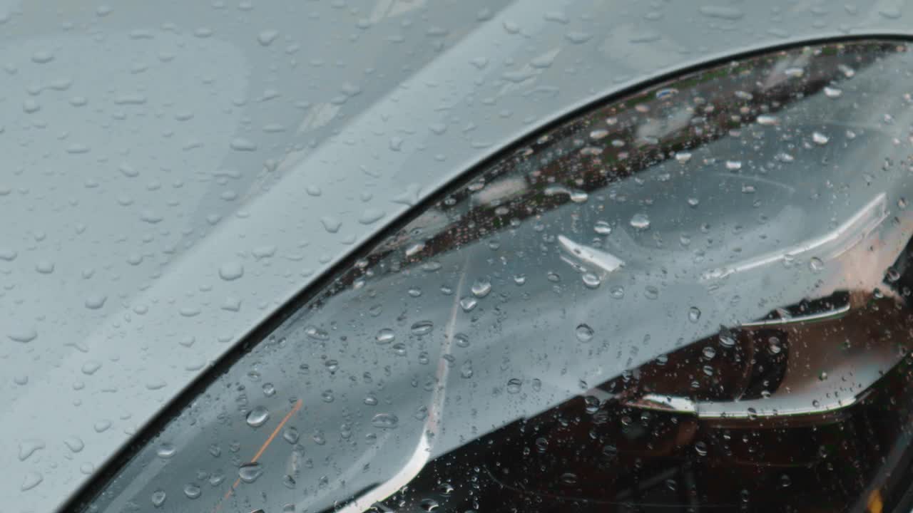 雨点落在汽车前灯的灰色视频素材