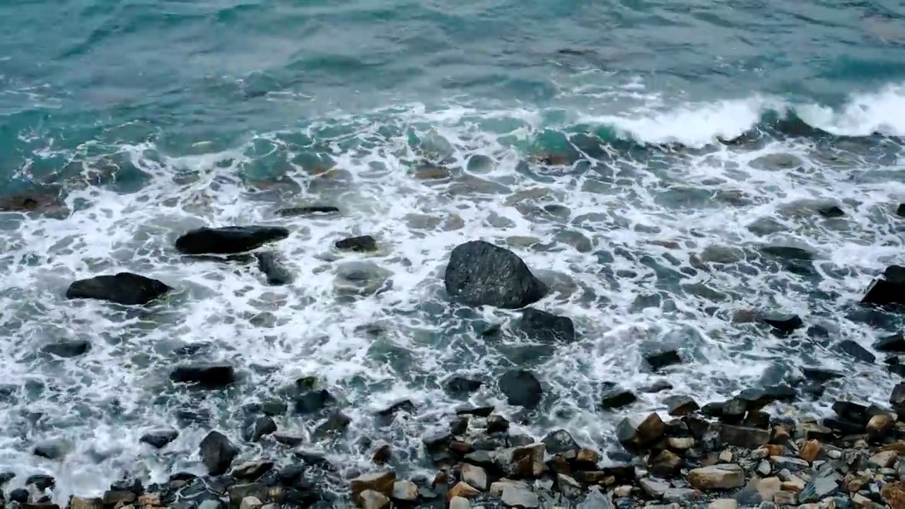 美丽的海浪的岩石海股票视频。从以上观点。多云天气下的岩石海滩。陷入困境的海洋视频下载