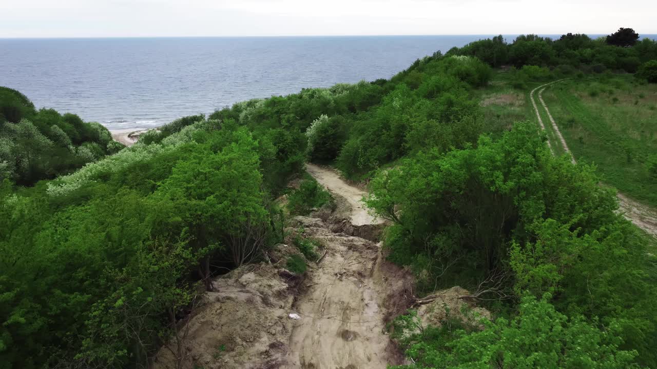 一条被毁坏的道路通向大海，悬崖后面生长着绿色植物视频素材