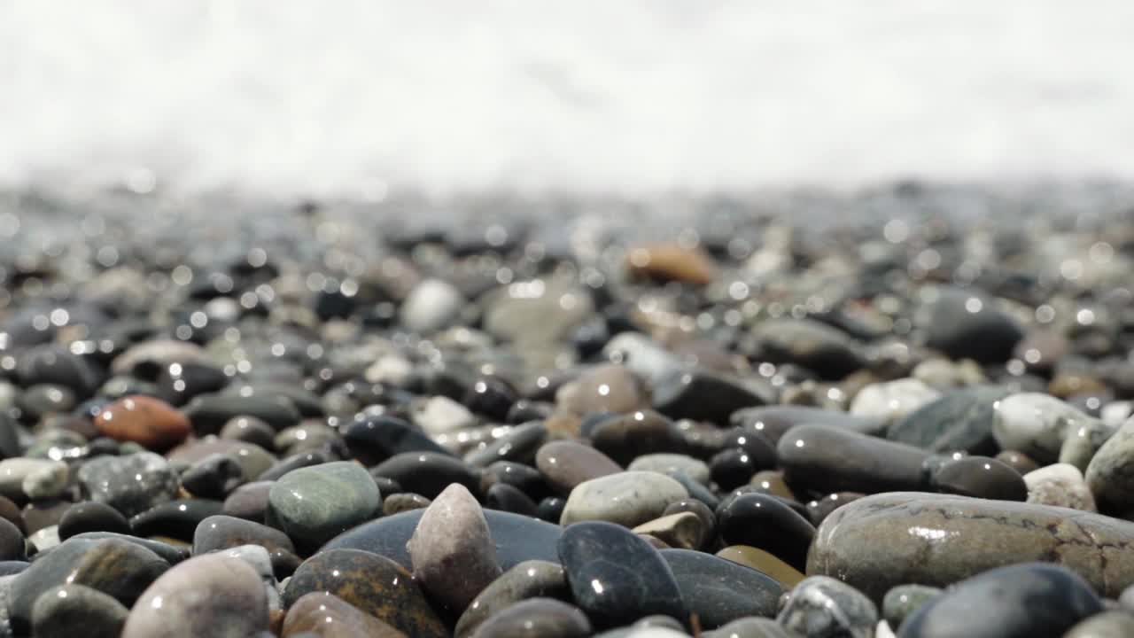 背景是被海水冲刷过的闪亮的小海石。视频素材