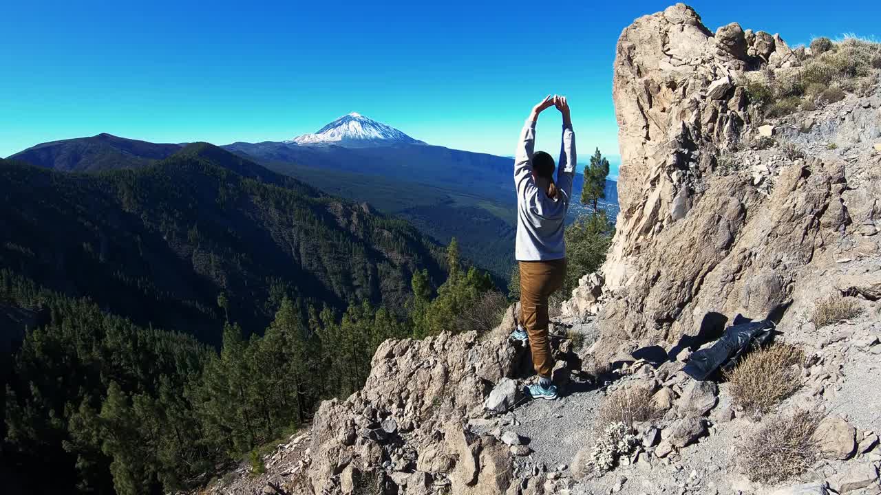 一位年轻的妇女爬上了山顶。她把手举在空中。深吸新鲜空气，欣赏雪峰美景。自由,灵感视频素材