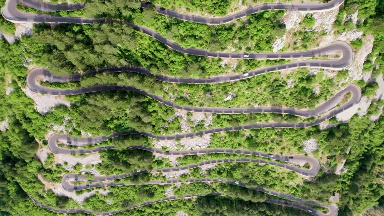 鸟瞰图的山蜿蜒的道路与许多移动的汽车。道路上坡，有许多急转弯。汽车和摩托车沿着山路行驶视频素材