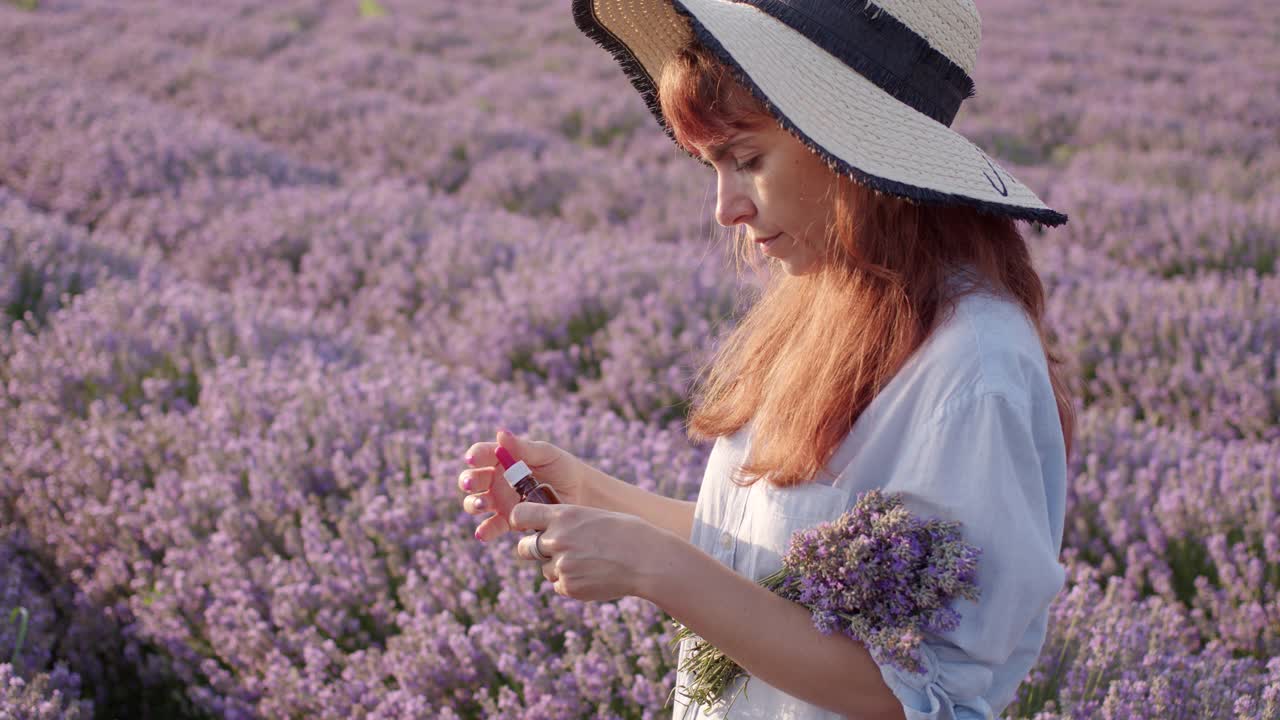 护肤化妆品薰衣草油瓶上薰衣草田。一个女农民拿着一个滴管，把油滴在手上。天然生态化妆品。视频素材