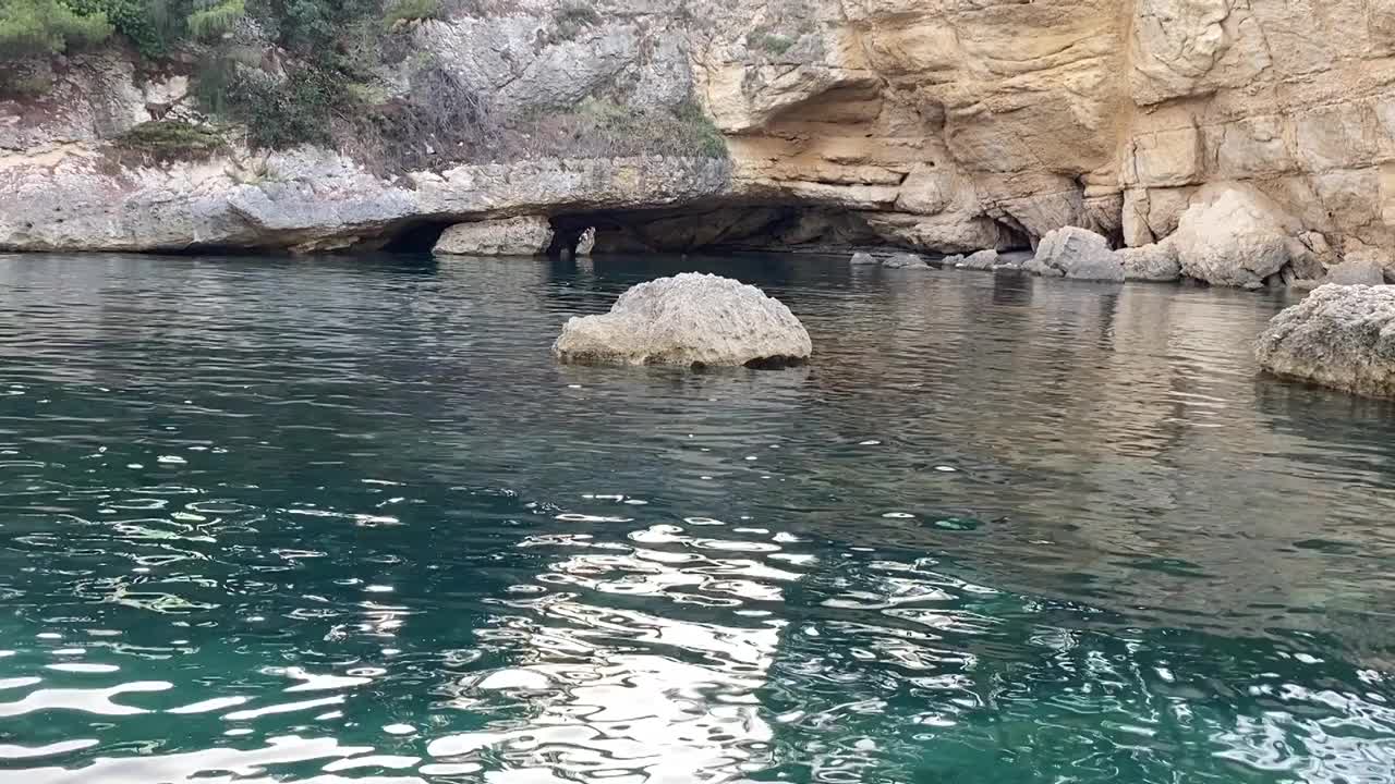 天堂海泻湖与神秘的洞穴洞穴的海岸岩石。美丽的地中海风景。夏夜碧绿闪亮的海景。壮观的石灰岩悬崖。视频素材