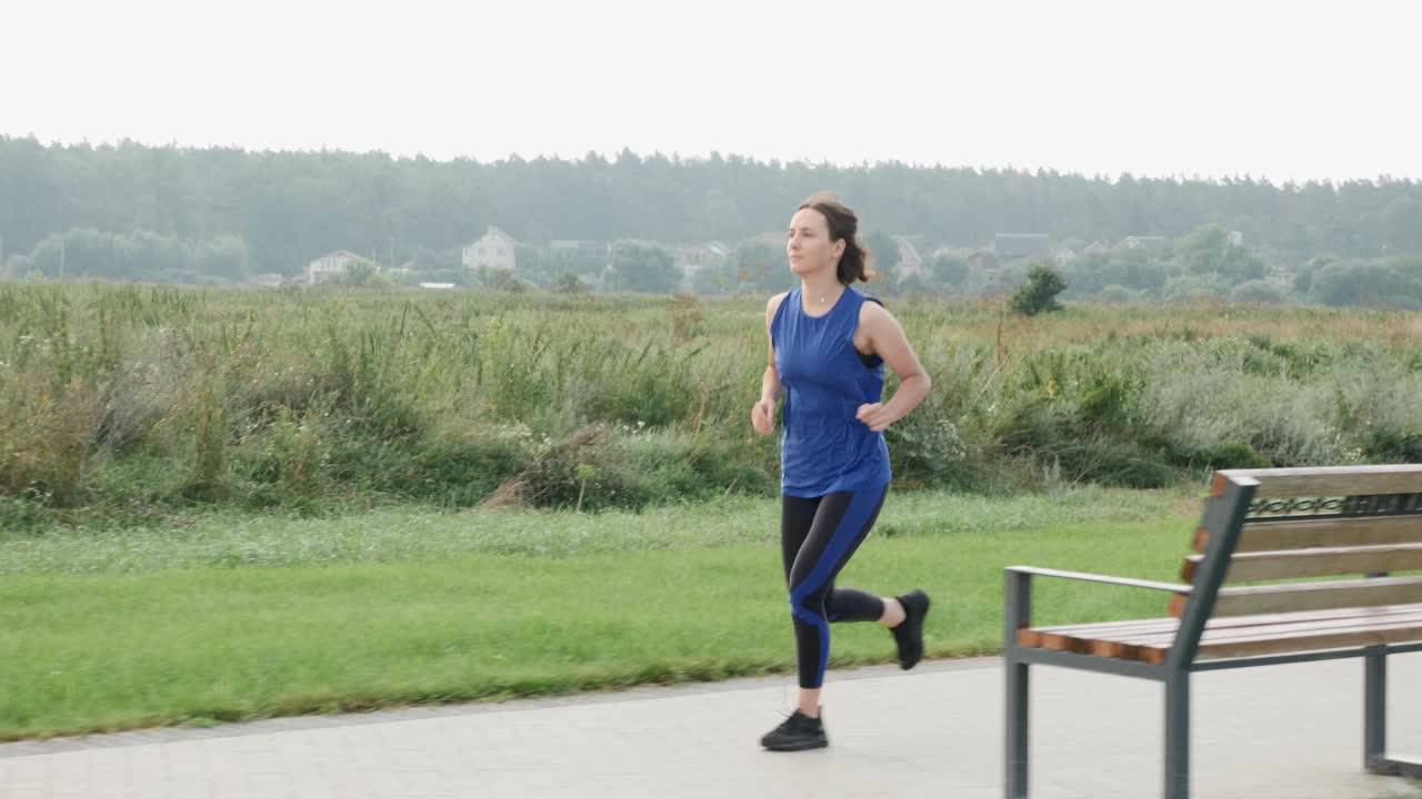 女性早上在城市公园慢跑。一个女人在跑步。健康的生活方式。耐力运动训练。慢跑锻炼运动员的腿。慢跑者健身运动跑步视频素材