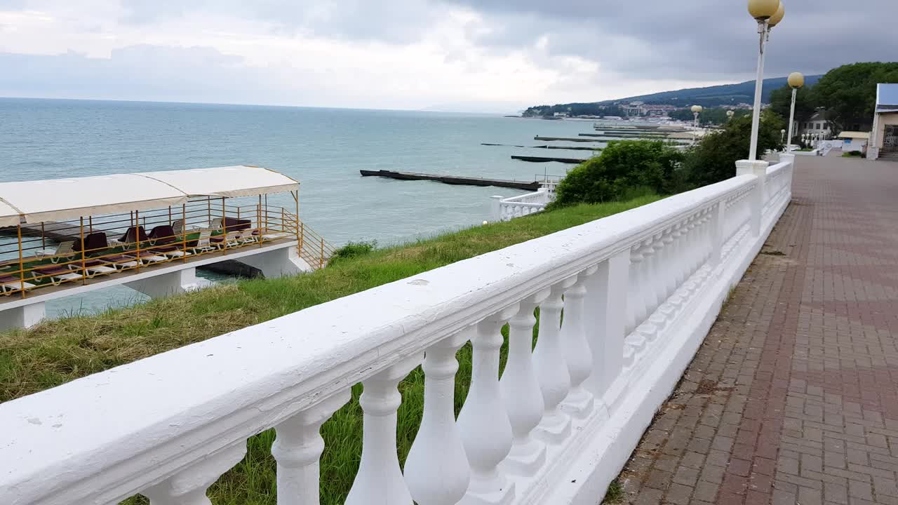 4K视频，经典的白色栏杆上的堤岸与大海的背景。夏日多云的黎明，美丽的海景，空旷的晨间散步视频素材