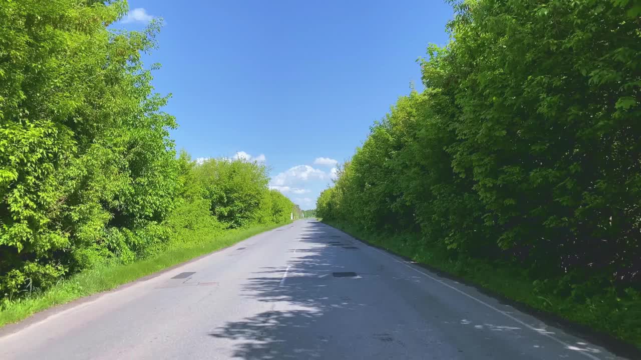 在晴朗的日子里，一条风景优美的道路，在明亮的绿树之间。汽车旅游和旅游的概念。视频素材