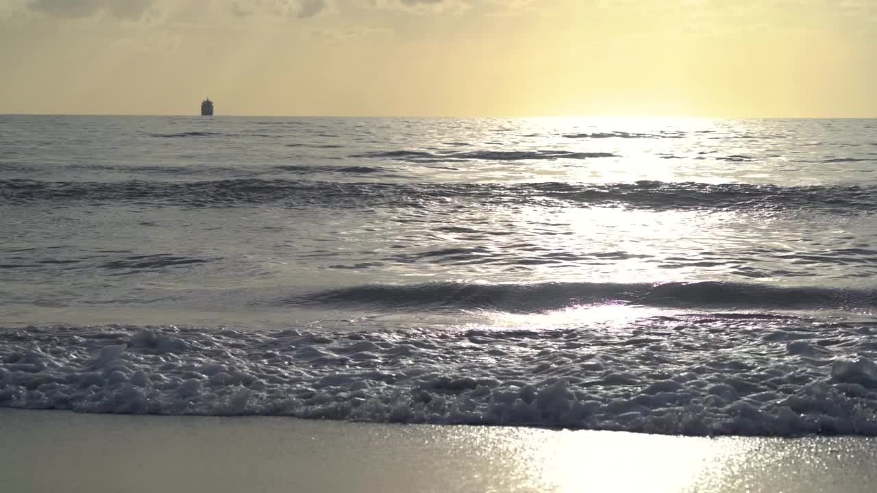 橙色的日落天空在海上和波浪翻滚的管道撞击海滩。视频素材