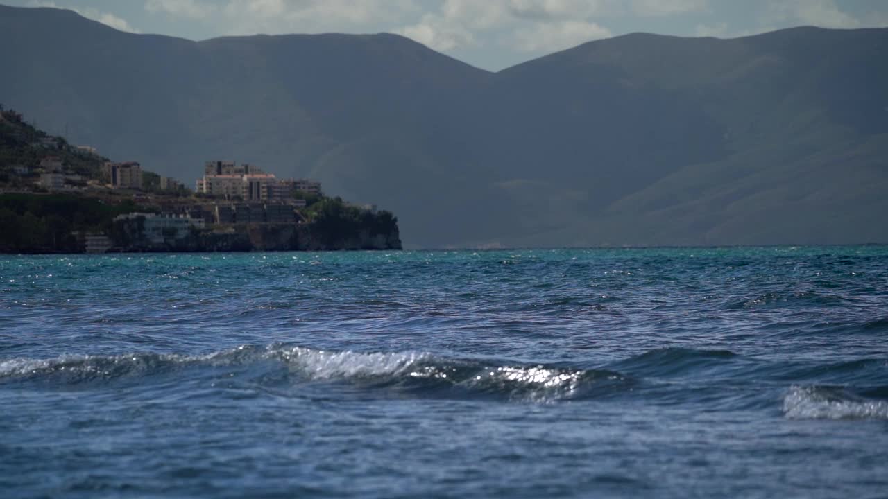 以海浪、小城市和巨大的自然山脉为背景的海景。视频素材