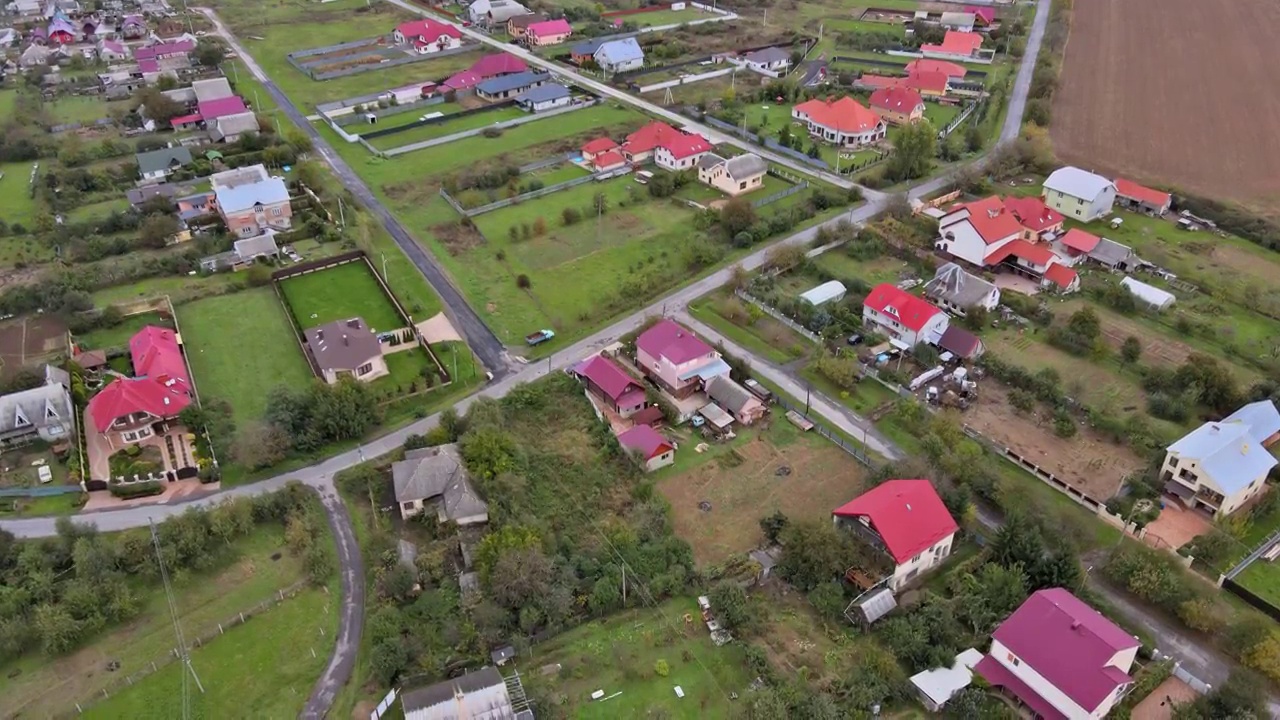 从高处鸟瞰美丽的乡村房屋和街道，耕地，草地视频素材