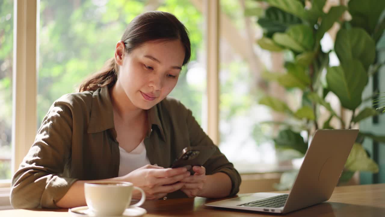 亚洲女人在咖啡馆用智能手机视频素材