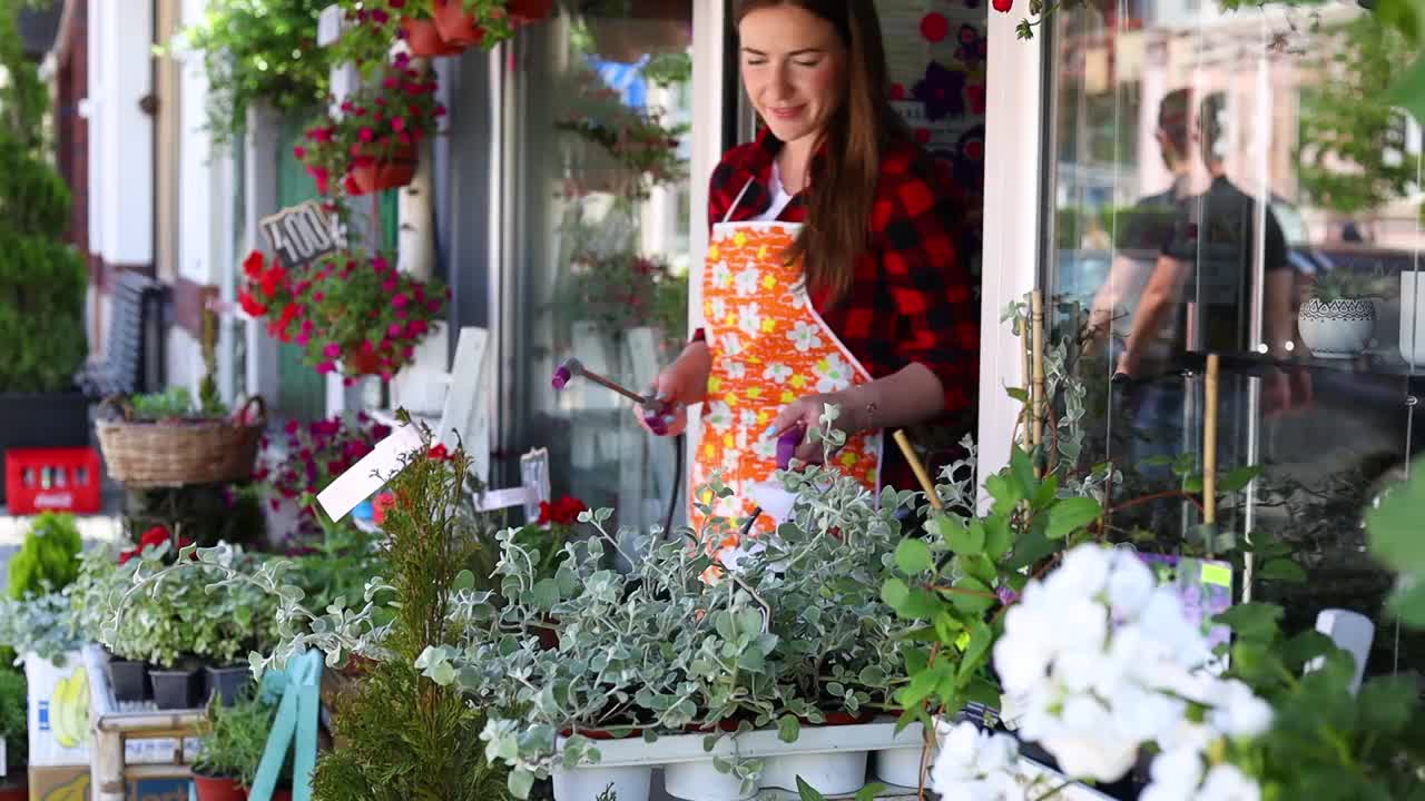 在城市街头花店或花店工作的年轻成年妇女。视频素材