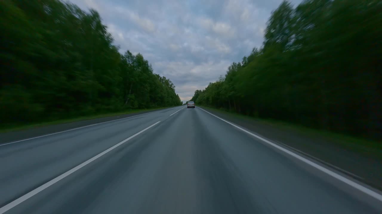 区际高速公路上的多云夜空。道路两旁生长着茂密的树木和灌木。乘汽车旅行。在运动。视频素材