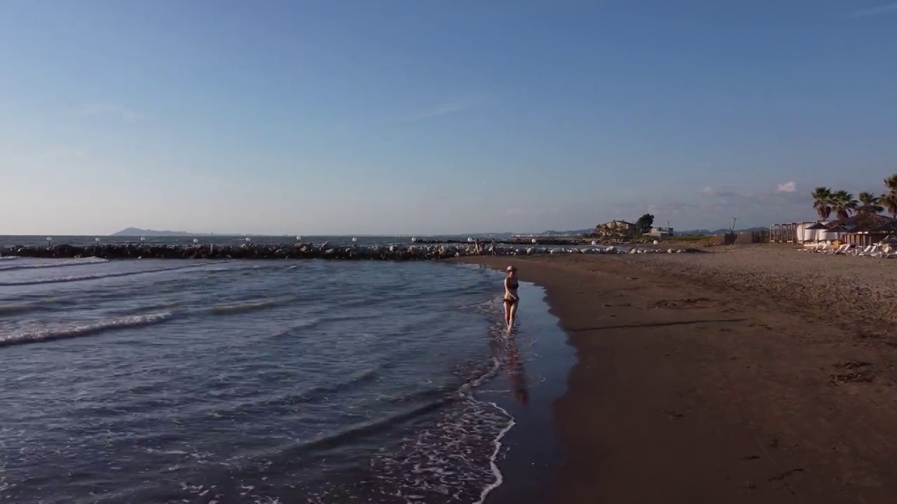 在海滩上散步的女人。女人的行为好玩和邀请，有乐趣的假期。旅行的概念。视频素材