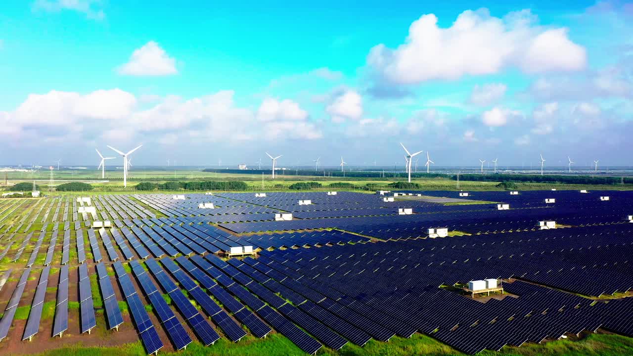 平原地区的太阳能发电站和远处的风力涡轮机。中国江苏省盐城市视频素材