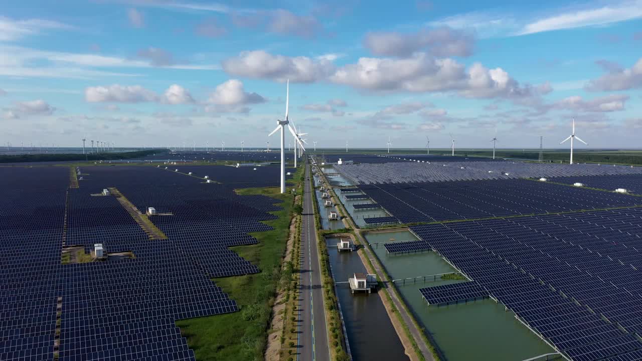 平原地区的太阳能发电站和远处的风力涡轮机。中国江苏省盐城市视频素材