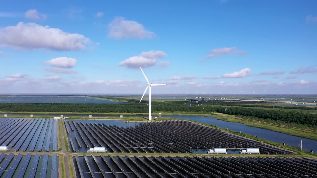 平原地区的太阳能发电站和远处的风力涡轮机。中国江苏省盐城市视频素材