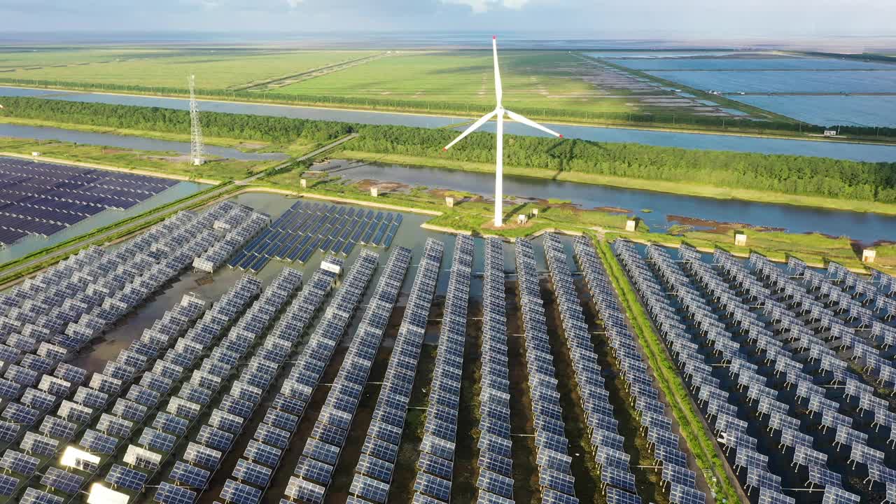 平原地区的太阳能发电站和远处的风力涡轮机。中国江苏省盐城市视频素材