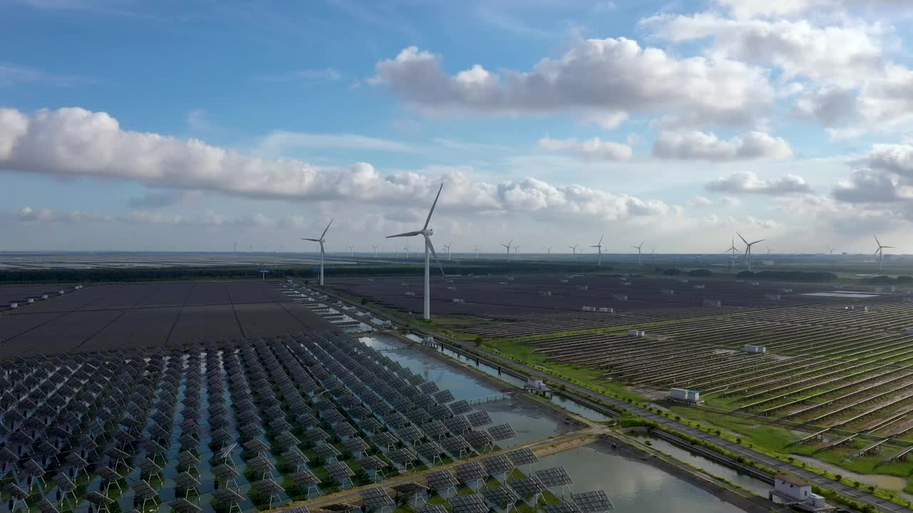 平原地区的太阳能发电站和远处的风力涡轮机。中国江苏省盐城市视频素材