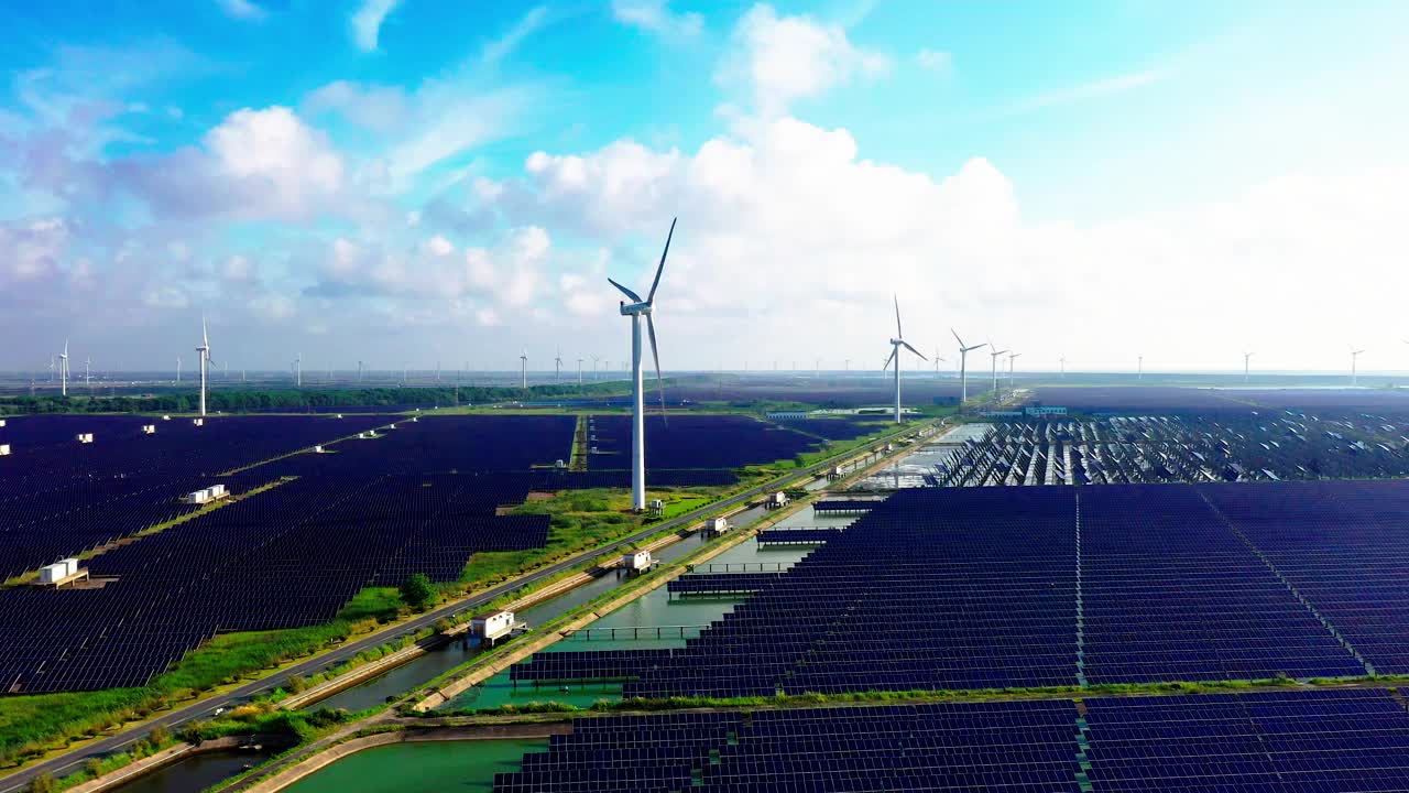 平原地区的太阳能发电站和远处的风力涡轮机。中国江苏省盐城市视频素材