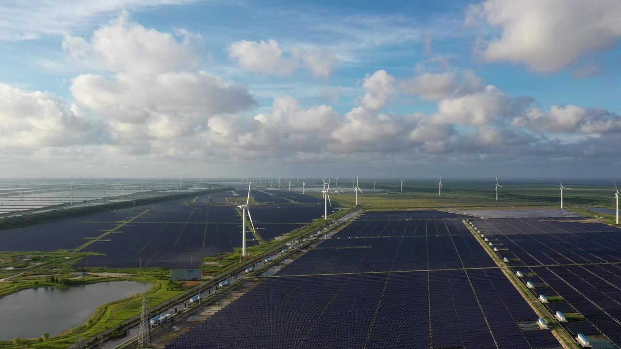 平原地区的太阳能发电站和远处的风力涡轮机。中国江苏省盐城市视频素材