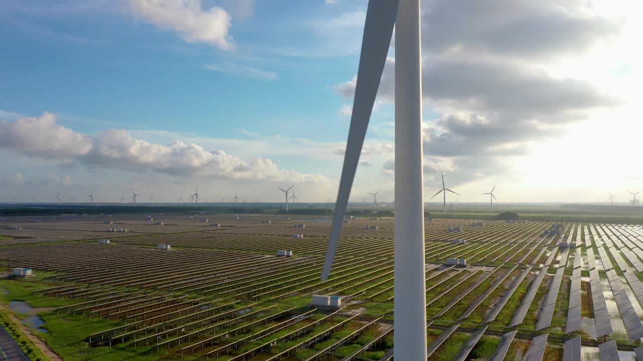 高大的风力涡轮机正在运转，地面上的太阳能发电站也在运转。中国江苏省盐城市视频素材