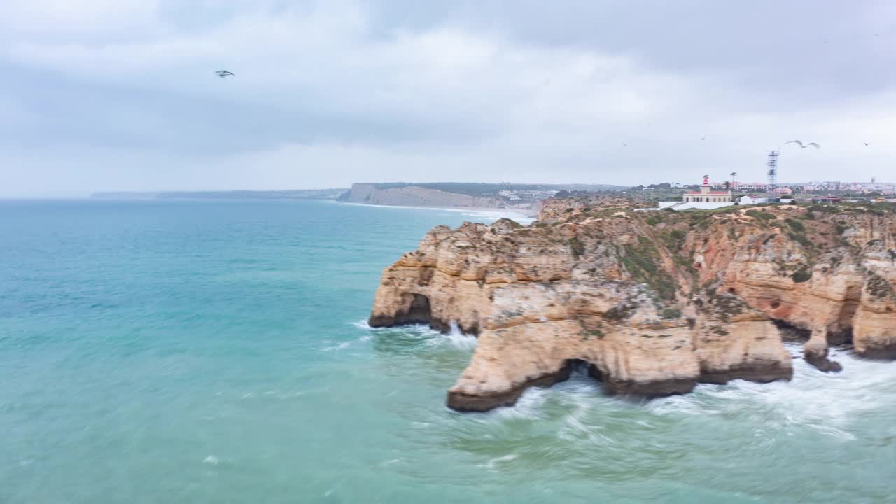 空中无人驾驶飞机盘旋在美丽的拉戈斯阿尔加维海岸线上，海浪撞击岩石悬崖，多云的天视频素材