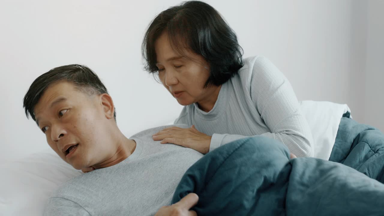 睡眠失眠。老男人醒来，妻子在一旁帮忙。手持。视频素材