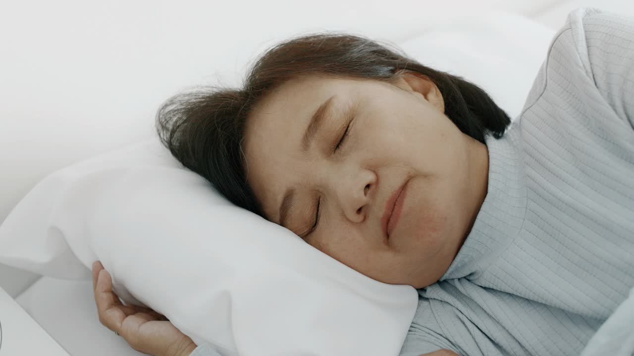 睡眠疾病。老女人睡不着觉，看着手机。手持拍摄的。视频素材