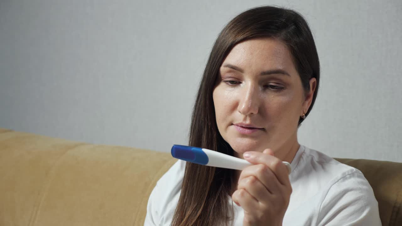 年轻女子高兴地看着验孕棒的特写镜头视频素材