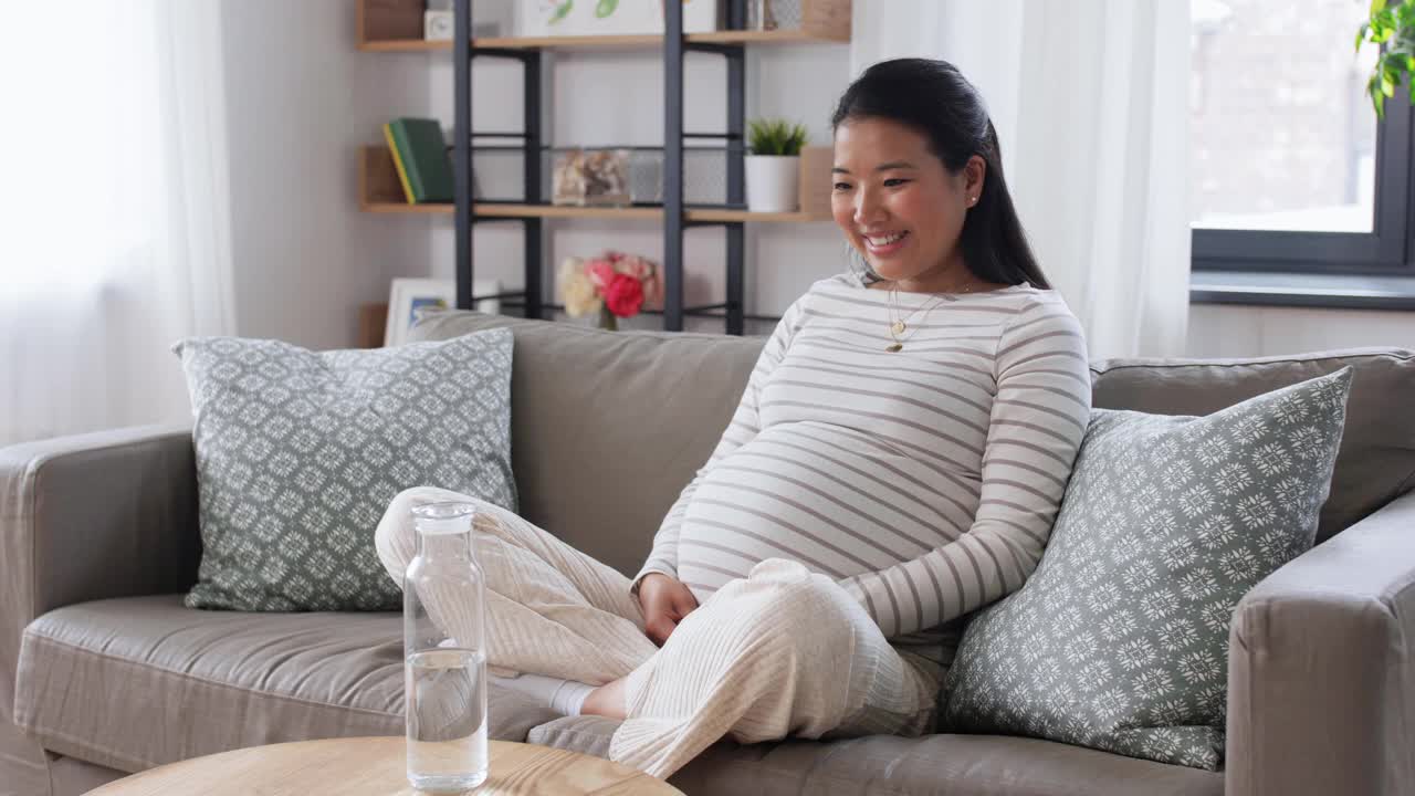 孕妇在家里用玻璃瓶盛水视频素材