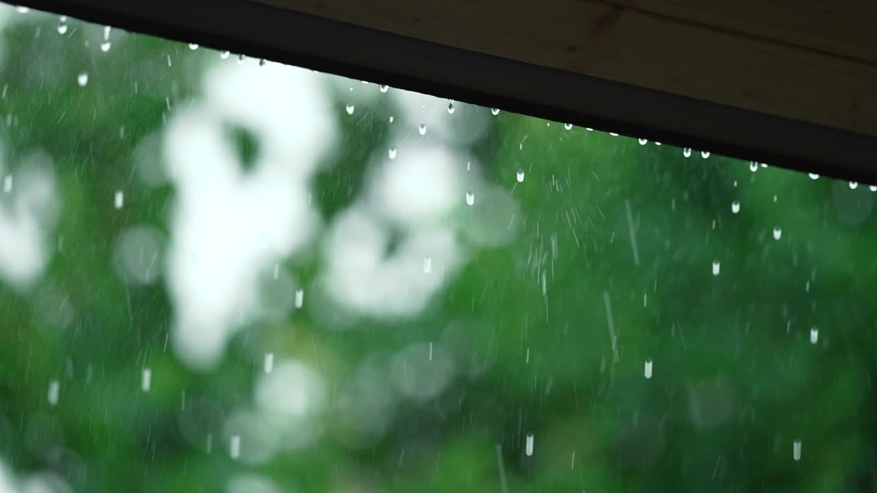 雨滴从木质屋顶的天篷落下。倾盆大雨在农村。潮湿的气候。秋高气爽。缓慢的绿色背景。视频素材