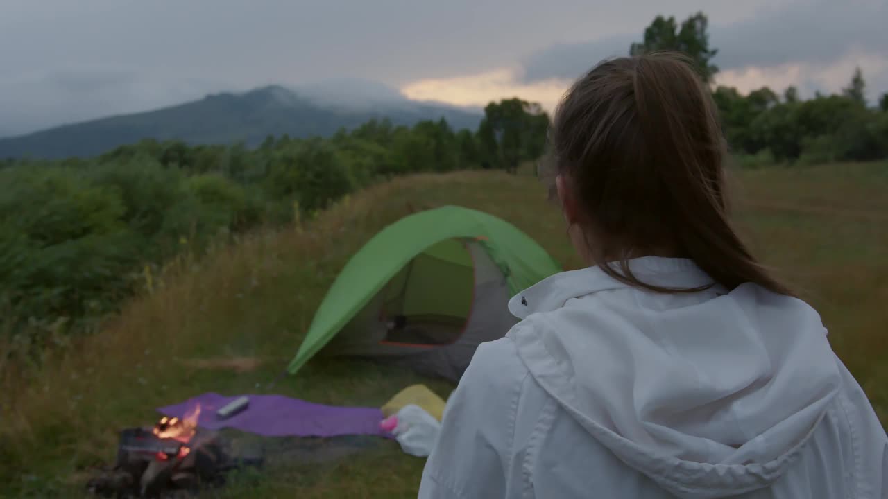 女人走在户外附近的露营帐篷和燃烧的火视频素材