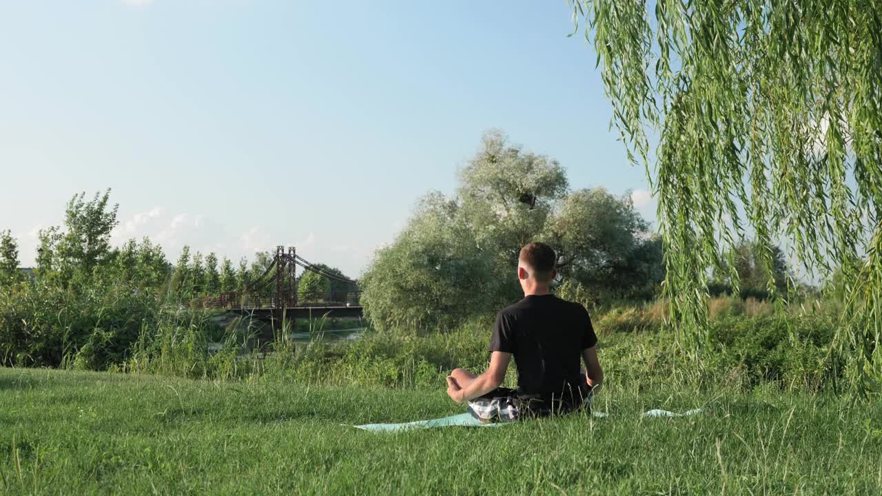 男人在早晨冥想，看着太阳，享受新鲜的空气和举起双手。年轻平和的男性在户外练习瑜伽视频素材