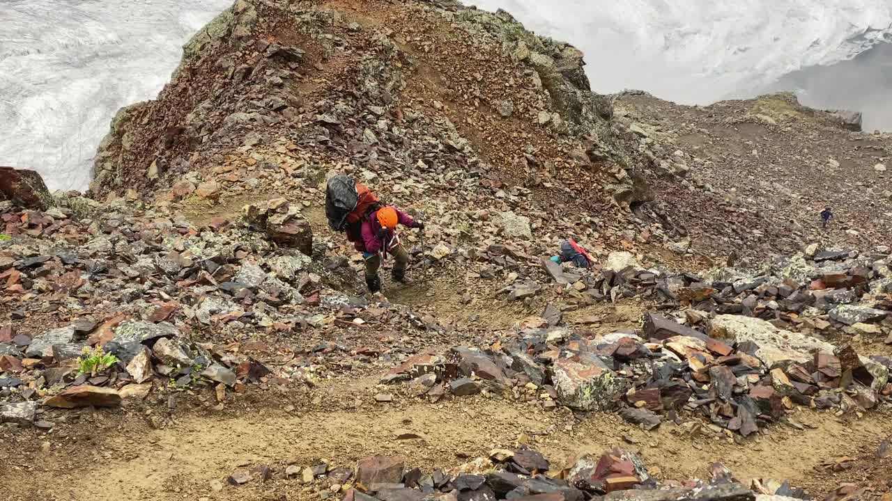 一个疲惫的游客沿着山路跌跌撞撞地经过巨石。视频素材