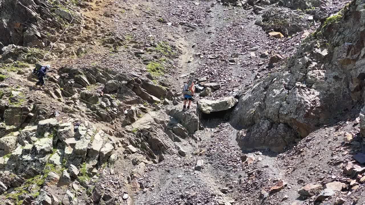 两个背着大背包的登山者抓住绳索从高山下来视频素材