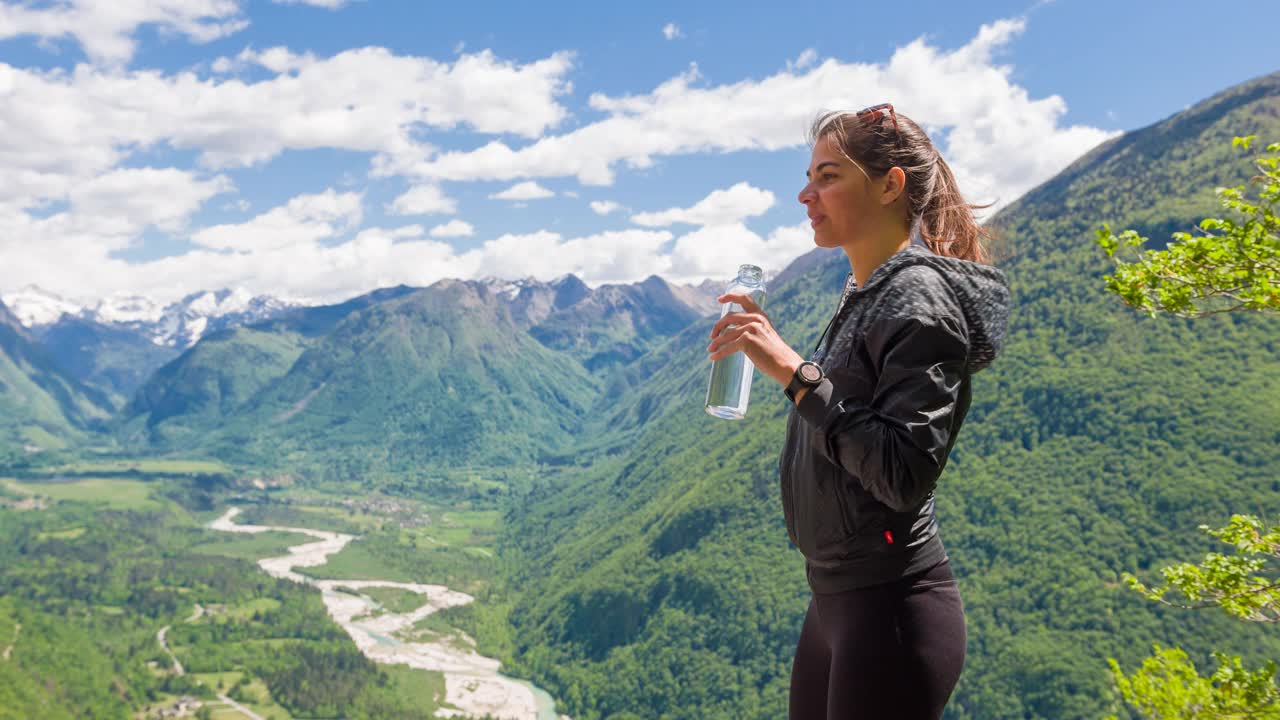 39、女子在山腰饮水，山谷在山腰背景视频素材