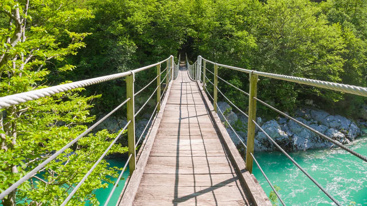 跨越木吊桥，横跨雄伟的绿松石河谷视频素材
