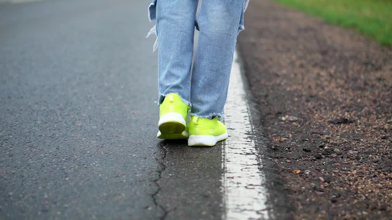 一个女孩在高速公路上走着，试图拦住一辆过路的汽车视频下载