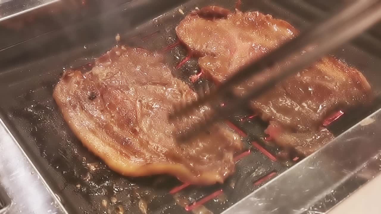 在豪华的韩式牛排烧烤(BBQ)餐厅里，新鲜的和牛牛肉在炭火上烧烤。视频下载